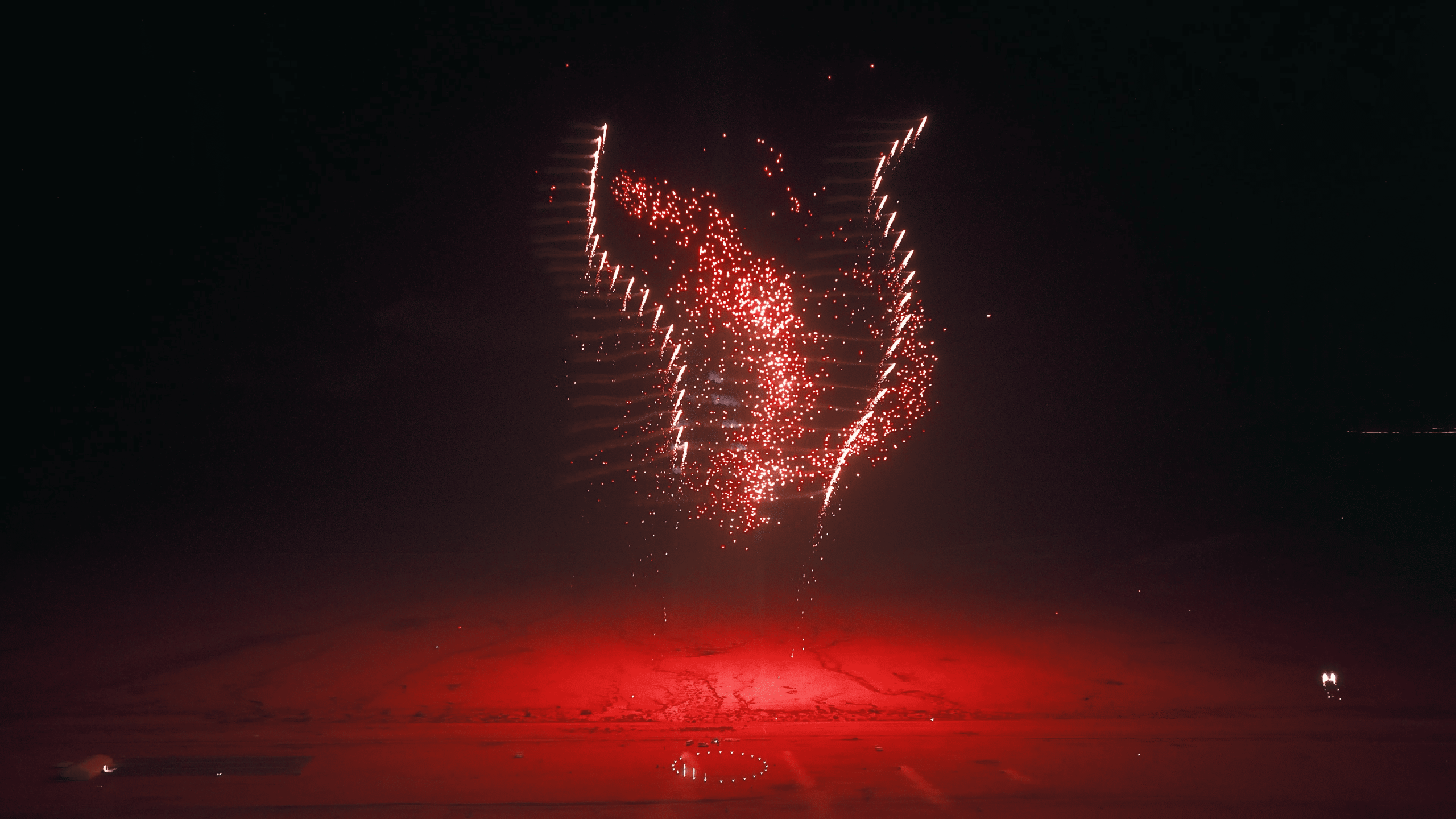 During the Lumasky drone show at the Saudi Aviation Club Sun and Fun Airshow 2025, drones form a dynamic figure of red luminous dots in the night sky, hovering over the illuminated airfield area.