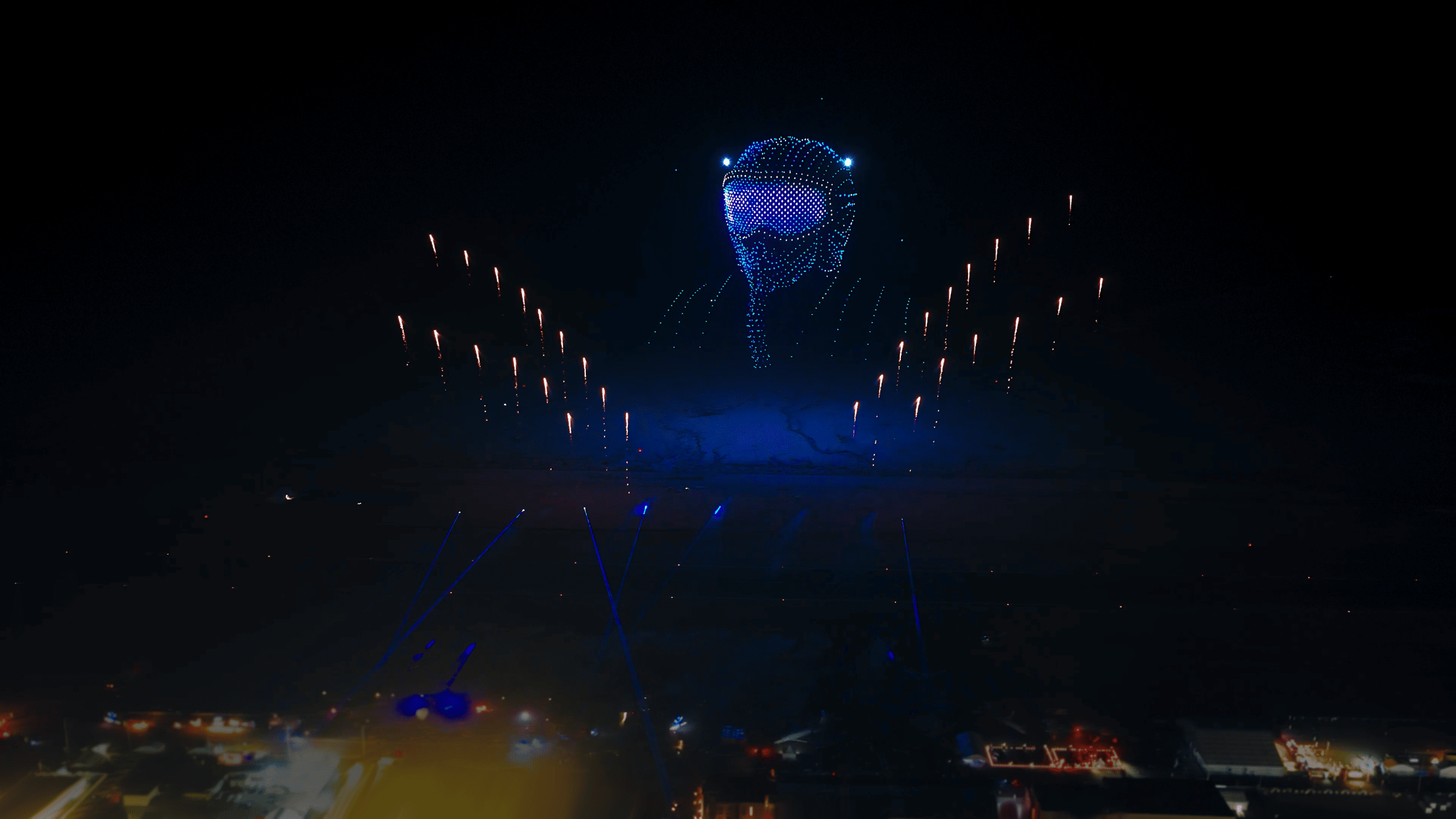 During the Lumasky drone show at the Saudi Aviation Club Sun and Fun Airshow 2025, drones form a light portrait in the night sky, surrounded by symmetrical golden lights and searchlight beams above the airfield.
