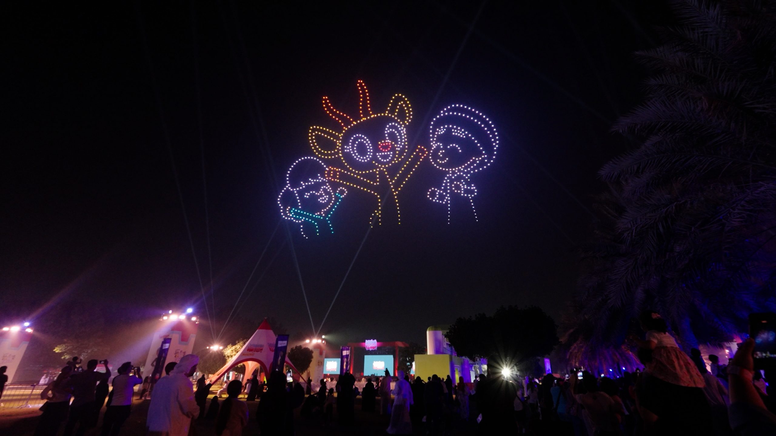 During the 800 Drone Light Show for The Mansour Festival in Abu Dhabi, drones create colorful cartoon characters in the night sky, illuminated by colorful lights, above the stage and the audience.